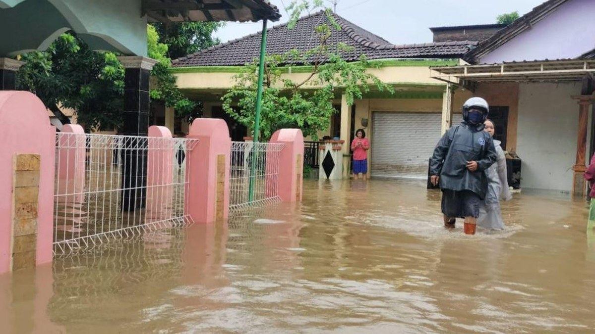 Warga berjalan menembus banjir yang merendam permukiman di Desa Sowan, Kabupaten Jepara, Jawa Tengah